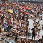 Over-consumption and over-population : Crowds of sun seekers fill the beach