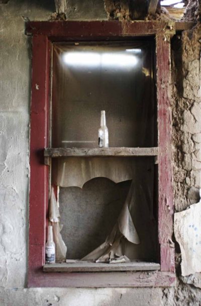 Where torn curtains have blown through a shattered window. photo by Damon Falke