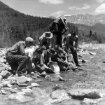 Prospector Marshall Long showing boys how to pan for gold in La Plata Creek