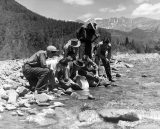 Prospector Marshall Long showing boys how to pan for gold in La Plata Creek