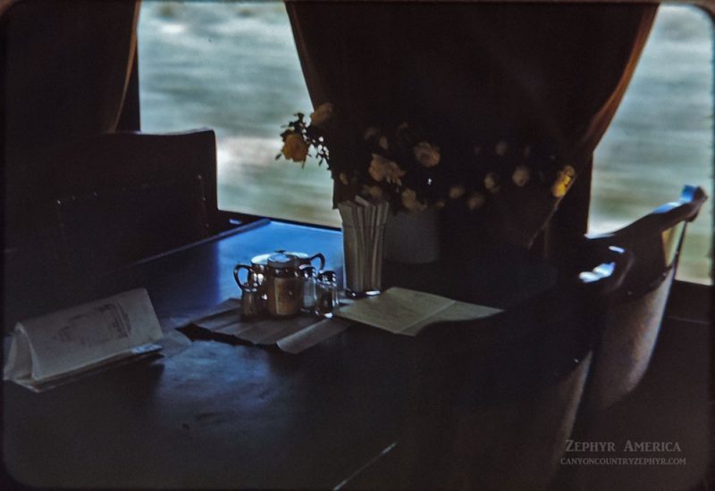 In the Dining Compartment. The conductor picked roses at Gato and put them in a vase for the passengers. 1948. Photo by Herb Ringer